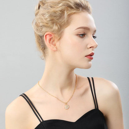 Woman wearing a gold necklace with a delicate pendant on a gray background