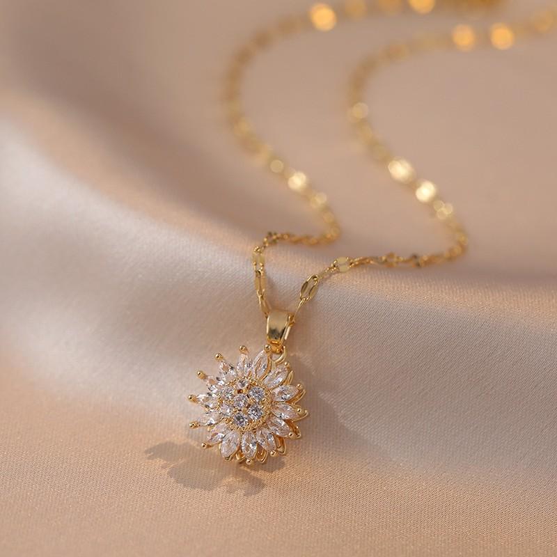 Gold necklace with a floral pendant on a beige fabric background