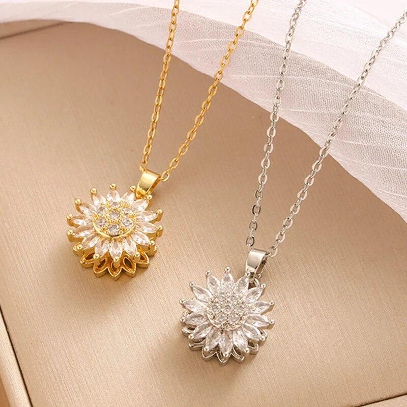 Two sunflower-shaped pendants, one gold and one silver, on a beige surface.