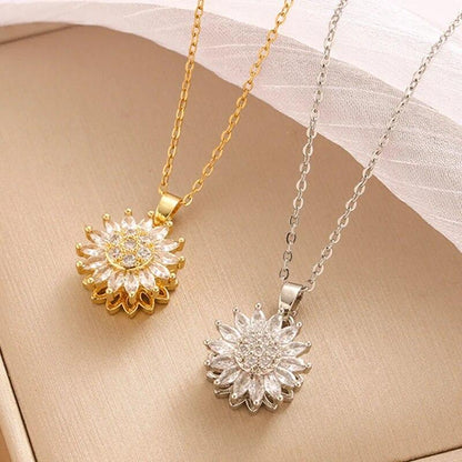 Two sunflower-shaped pendants, one gold and one silver, on a beige surface.
