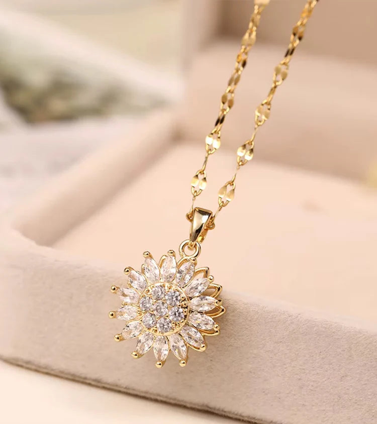Gold necklace with a sunflower-shaped pendant on a soft beige background
